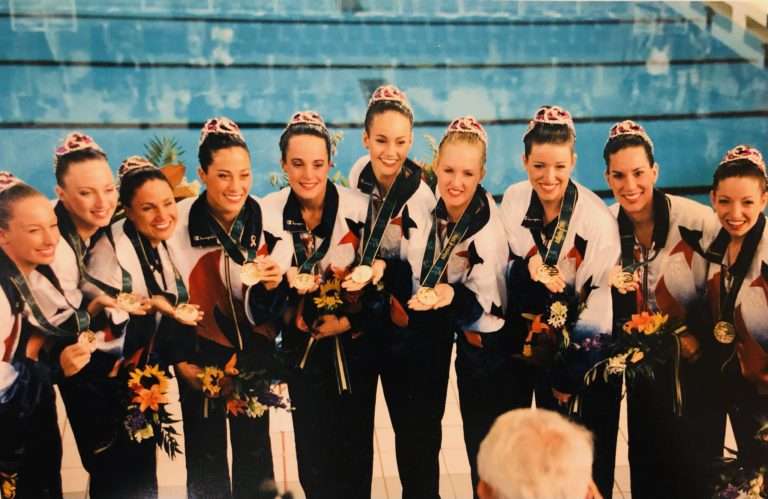 A photo showing the Synchronized artistic swimming 1996 Olympic Gold Medalists displaying their medalss to the crowd after the awards ceremony Suzannah Bianco is part of this team
