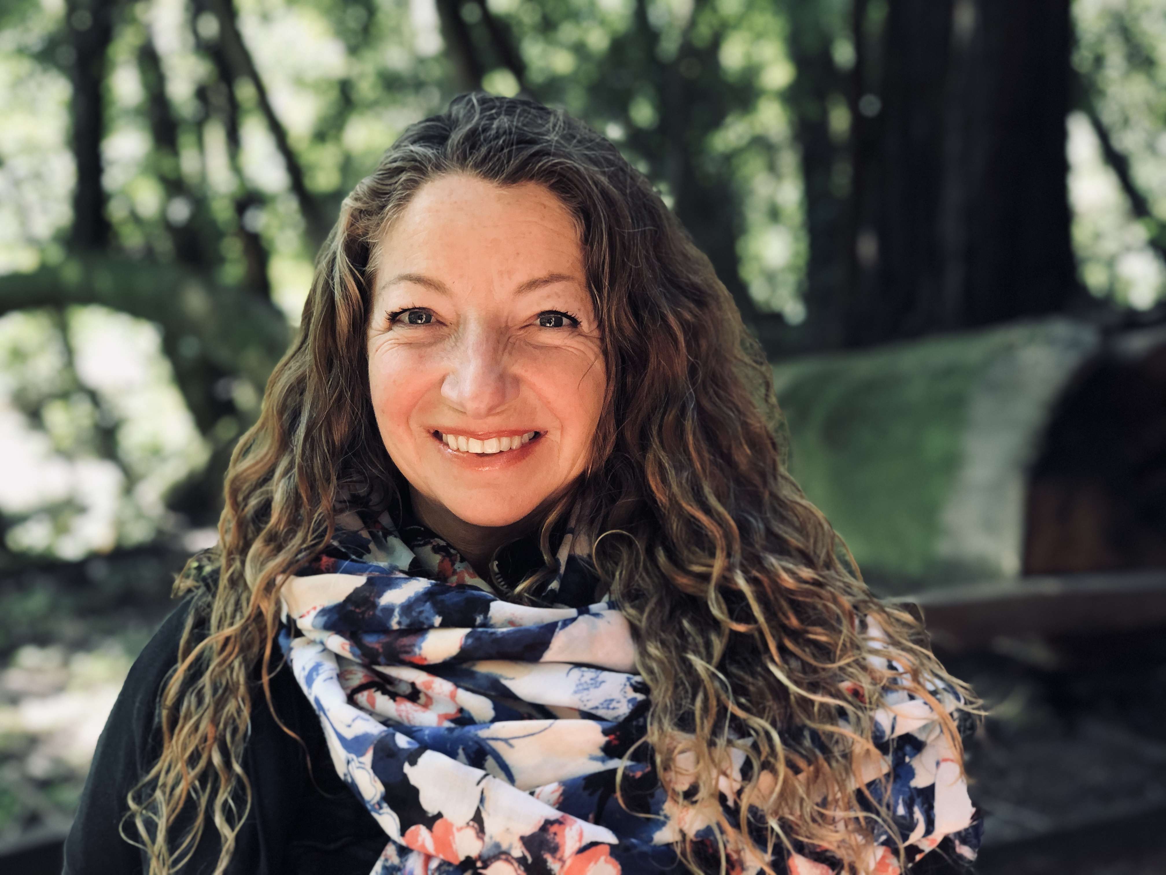 photo of Suzannah Bianco health coach and founder of powerful perimenopause is in the redwood forest wearing a multi colored scarf and black shirt